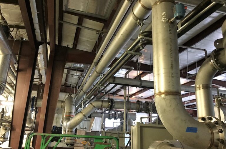 Installed industrial piping inside a gas processing facility showing field installation, supports, valves, and process system integration.