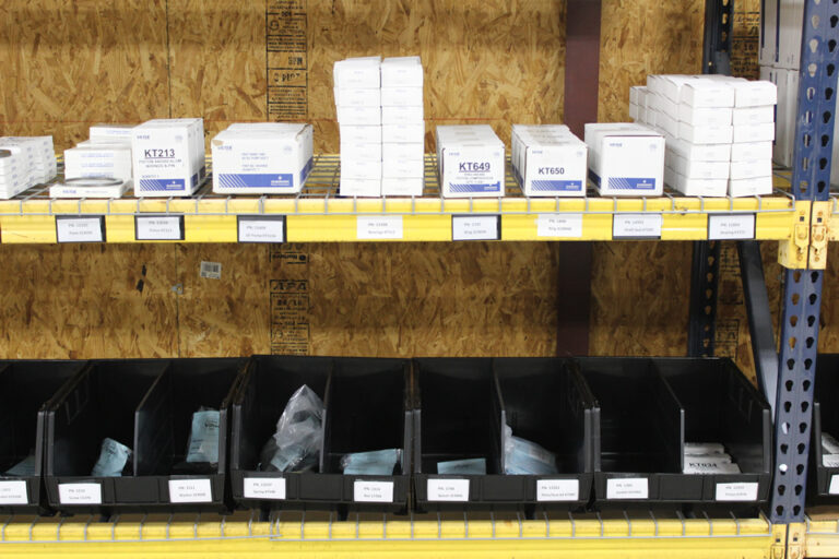 Compressor parts inventory with filters, valves, mechanical internals, seals, and labeled storage bins for gas processing equipment service.