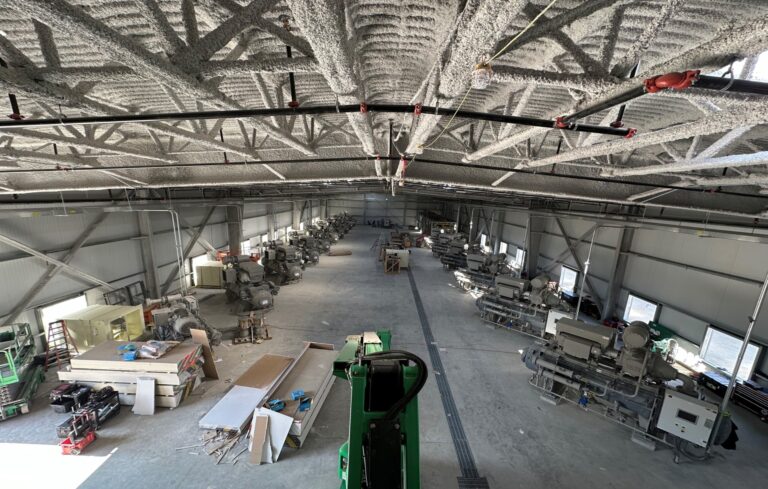 Industrial field installation facility with multiple compressor packages, skidded systems, piping, controls, and process equipment staged for installation.