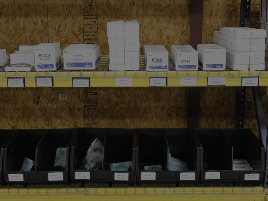 Organized compressor replacement parts inventory with boxed components, filters, valves, seals, and labeled storage bins.