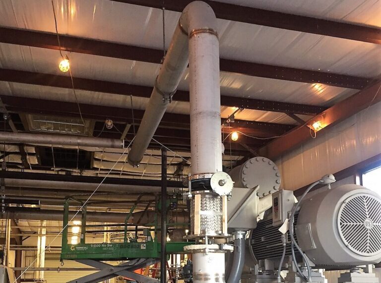 Technician inspecting gas processing package equipment, piping, vessels, and compressor system during field service support.